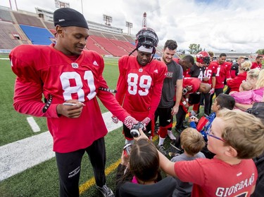 Bakari Grant (L) and DaVaris Daniels sign autographs for Make-A-Wish Foundation kids after a Stamps practice at McMahon Stadium in Calgary, Alta., on Thursday, Aug. 25, 2016. About 30 kids with the Make-A-Wish Foundation of Southern Alberta watched a team practice, toured the Stampeders' locker room and met the players. Lyle Aspinall/Postmedia Network