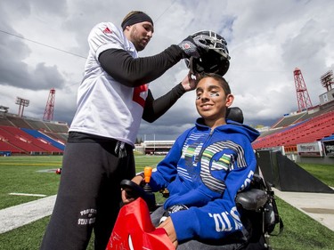 Ishan Manerikar, 15, tries on Adam Thibault's helmet after Calgary Stampeders practice in Calgary, Alta., on Thursday, Aug. 25, 2016. About 30 kids with the Make-A-Wish Foundation of Southern Alberta watched a team practice, toured the Stampeders' locker room and met the players. Lyle Aspinall/Postmedia Network
