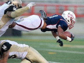 Calgary  Colts running back Xavier Ramsay catches some air while being taken down in the first quarter as the Calgary Colts played host to the Edmonton Huskies in Prairie Junior Football League at McMahon Stadium on September 26, 2015.