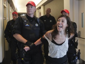 A protester is removed from the National Energy Board public hearings into the Energy East pipeline in Montreal on Monday.