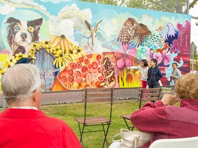 Hana Jansen points at part of the new mural in Brentwood on Northmount Drive N.W. in Calgary, on August 28, 2016. She along with Alasdair MacDonald to her left, and Sarah MacDonald, behind them, helped the artist paint portions of the mural.