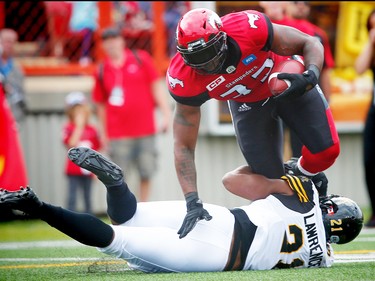 Calgary Stampeders Jerome Messam is tackled by Simoni Lawrence of the Hamilton Tiger-Cats during CFL football in Calgary, Alta., on Sunday, August 28, 2016. AL CHAREST/POSTMEDIA