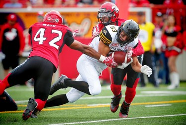 Hamilton Tiger-Cats Andy Fantuz is tackled by Deron Mayo and Joe Burnett during CFL football in Calgary, Alta., on Sunday, August 28, 2016. AL CHAREST/POSTMEDIA