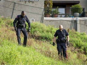 Police comb a steep grassy embankment near the 300 block of 1 Ave NE in Calgary, Alta., on Sunday, Aug. 7, 2016. They were investigating a suspicious death. Lyle Aspinall/Postmedia Network