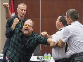 Security guards try to restrain a demonstrator from interrupting the National Energy Board public hearing into the proposed $15.7-billion Energy East pipeline project on Monday, August 29, 2016 in Montreal.