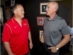 University of Calgary Dinos coach Wayne Harris, left, chats with his new defensive coordinator Tom Higgins during a media availability in Calgary  on Thursday, Aug. 11, 2016.