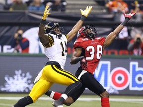 Calgary Stampeders Buddy Jackson and the Ticats' Terrell Sinkfield reach for a pass during the 2014 Grey Cup in Vancouver.