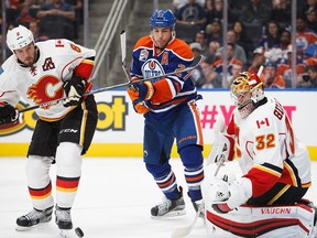 Milan Lucic (27) of the Edmonton Oilers looks for a shot against goaltender Jon Gillies as Nicklas Grossman (8) of the Calgary Flames looks on during a preseason NHL game on September 26, 2016 at Rogers Place in Edmonton, Alberta, Canada.