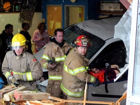 Rescue workers help an injured child after a minivan crashed into a school in St.Paul, Alta., Thursday, Oct.25, 2012. Police say a child was pinned under the minivan after it went through the wall of Racette Junior High School in St. Paul, east of Edmonton.THE CANADIAN PRESS/St.Paul Journal-Ryan McCracken MANDATORY CREDIT