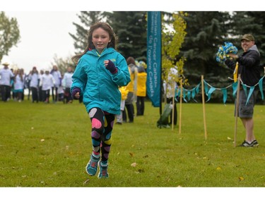 A young participant in the Ovarian Cancer Walk of Hope crosses the finish line at North Glenmore Park in Calgary, Alta., on Sunday, Sept. 11, 2016. Elizabeth Cameron/Postmedia