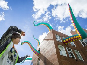 Elliot Trufyn, 9, poses for a playful photo with Tentacles, a piece by UK artists Filthy Luker and Pedro Estrellas, as it pokes out of a building in Inglewood as part of Beakerhead on Sunday.