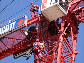 Firefighters lower a man who was at the top of a construction crane along 10th Avenue S.W. on Monday September 19, 2016.  Gavin Young/Postmedia