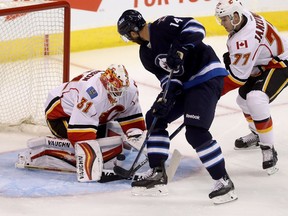Calgary Flames' goaltender Chad Johnson (31) stops Winnipeg Jets' Anthony Peluso (14) with Flames' Mark Jankowski (77) in front of the net during first period pre-season NHL hockey in Winnipeg, Tuesday, September 27, 2016.