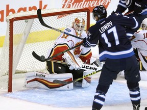 Calgary Flames' goaltender Chad Johnson (31) watches as Winnipeg Jets' Adam Lowry (17) tries to knock a puck out of the air during first period pre-season NHL hockey in Winnipeg, Tuesday, September 27, 2016.