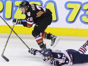 Calgary Hitmen Tyler Mrkonjic skates past a sprawling Tri-City Americans Parker Wotherspoon in WHL action at the Scotiabank Saddledome in Calgary, Alta. on Saturday November 14, 2015. Mike Drew/Calgary Sun/Postmedia Network