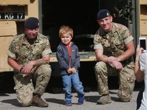 Charlie Dawson has his picture taken by his mom Allison along with British servicemen Corporal Richard Dellar, left, and Sergeant Charlie Corderoy and the armoured fighting vehicle on display Wednesday September 7, 2016 on the opening day of The Masters at Spruce Meadows. (Ted Rhodes/Postmedia)