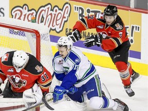 Cavin Leth of the Swift Current Broncos comes close on Calgary Hitmen goalie Cody Porter near defender Jake Bean in Calgary, Alta., on Sunday, Dec. 6, 2015. Jordy Stallard scored the Hitmen lucky goal against the Swift Current Broncos to fill the Saddledome with teddy bears from fans for sick and needy kids. Lyle Aspinall/Calgary Sun/Postmedia Network