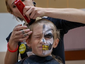 Cole Egan grimaces as Sally White of Tommy Gun's Barber Shop lops off his locks at the Shave Your Lid For A Kid event to raise money for cancer research at Southcentre Mall on Saturday.