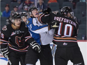 Dylan Stewart, centre, is sandwiched between Hitmen players Tristen Nielsen and Ty Prefontaine in Calgary, Alta., on Friday, Sept. 23, 2016.