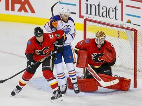 Dennis Wideman of the Calgary Flames and Zack Kassian of the Edmonton Oilers eye a shot on goalie Brian Elliott during NHL action in Calgary, Alta., on Monday, Sept. 26, 2016. It was the first pre-season game for both teams, a split-squad matchup with the other half of each team in the opposite city. Lyle Aspinall/Postmedia Network