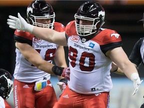 Calgary Stampeders' Quinn Smith, right, celebrates after sacking B.C. Lions' quarterback Jonathon Jennings, bottom, during the second half of a CFL football game in Vancouver, B.C., on Friday August 19, 2016.