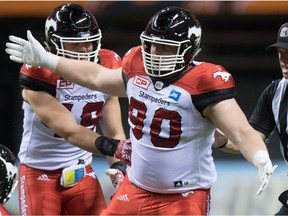 Calgary Stampeders' Quinn Smith, right, celebrates after sacking B.C. Lions' quarterback Jonathon Jennings, bottom, during the second half of a CFL football game in Vancouver, B.C., on Friday August 19, 2016.