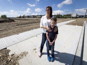 Monique Shaw and her son Luca Joint, 10, stand with open excavation near their home in the developing community of Sage Hill in Calgary, Alta., on Tuesday, Aug. 9, 2016. Shaw is frustrated the Calgary Board of Education's two closest bus stops for the upcoming school year would have her son either walking near open excavation or crossing the busy Symons Valley Road, which has no sidewalk on the east side. Lyle Aspinall/Postmedia Network