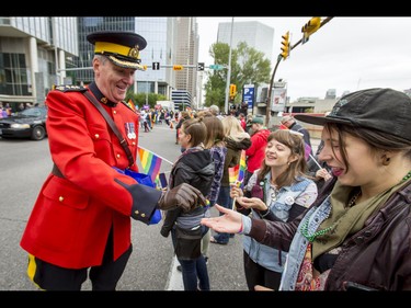 RCMP Chief Superintendent Tony Hamori hands out wristbands during the Calgary Pride Parade in the city's downtown core on Sunday, Sept. 4, 2016. About 60,000 people were expected to watch the annual parade, as more than 125 entries took part. Lyle Aspinall/Postmedia Network
