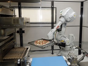 In this Monday, Aug. 29, 2016 photo, a robot places a pizza into an oven at Zume Pizza in Mountain View, Calif. The startup, which began delivery in April, is using intelligent machines to grab a slice of the multi-billion-dollar pizza delivery market.