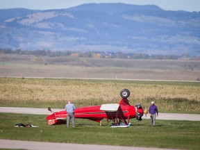 A bi-plane sits on its roof next to a runway at the Springbank Airport west of Calgary on Tuesday, Sept. 13, 2016. A witness said the plane veered left and struck its propeller before flipping over, but the occupants appeared to be unhurt.