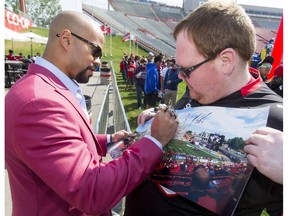 Recently retired star Jon Cornish signs a photo for fan Kent Johnson during the Calgary Stampeders Fanfest at McMahon Stadium in Calgary, Alta., on Saturday, May 14, 2016.