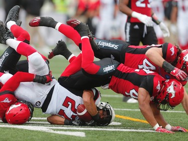 Ottawa Redblacks Kienan Lafrance is tackled by Brandon Smith, Deron Mayo and Alex Singleton of the Calgary Stampeders during CFL football in Calgary, Alta., on Saturday, September 17, 2016.