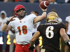 University of Calgary Dinos QB Jimmy Underdahl (left) releases a pass under pressure from University of Manitoba Bisons DE Evan Foster during Canada West football action in Winnipeg on Sept. 1, 2016.