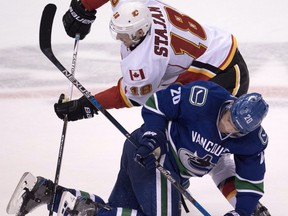 Calgary Flames centre Matt Stajan (18) and Vancouver Canucks centre Brandon Sutter (20) fight for control of the puck during third period NHL action, in Vancouver on Saturday, Oct. 15, 2016.