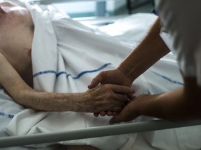 (FILES) A file picture taken on July 22, 2013 shows a nurse holding the hand of an elderly patient at the palliative care unit of the Argenteuil hospital, outside Paris. A panel set up at the request of President Francois Hollande on December 16, 2013 recommended legalising assisted suicide in France, where the debate on euthanasia has re-emerged after several end-of-life tragedies. The suicides of two elderly couples in November and the heartwrenching testimony of a politician who watched her terminally-ill mother die after taking pills have shocked and moved France, where euthanasia is illegal.AFP PHOTO / FRED DUFOURFRED DUFOUR/AFP/Getty Images ORG XMIT: POS1312161151512310 ORG XMIT: POS1504101413518393 // 1211 na euthanasia ORG XMIT: POS1511261852413923 // 0116 na dying