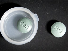 A genuine oxycodone pill (R) is shown next to a fake oxy pill containing fentanyl during a fentanyl processing demonstration at the Calgary Police Service headquarters in Calgary, Alta., on Monday, Oct. 17, 2016.