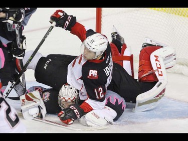Calgary Hitmen goalie Cody Porter is tackled by Prince George Cougars Jensen Harkins in WHL action at the Scotiabank Saddledome in Calgary, Alberta, on Saturday, October 29. The Hitmen beat the Cougars in overtime 3-2. Mike Drew/Postmedia