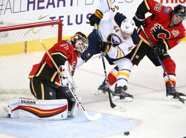 Calgary Flames goalie Chad Johnson, left, stops a shot on net from Buffalo Sabres Nicolas Deslauriers, middle as Flames Sean Monahan helps, right, in NHL hockey action at the Scotiabank Saddledome in Calgary, Alta. on Tuesday October 18, 2016. Leah Hennel/Postmedia