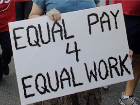 A woman carries a sign for equal pay as she marches with other protestors in support of raising the minimum wage to $15 an hour as part of an expanding national movement known as Fight for 15, Wednesday, April 15, 2015, in Miami. The event was part of a national protest day to coincide with the April 15 deadline for filing income taxes.