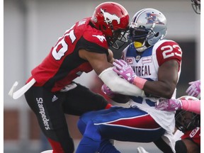 Montreal Alouettes' Brandon Rutley, centre, is brought down by Calgary Stampeders' Glenn Love, left, and Ja'Gared Davis during first half CFL football action in Calgary, Saturday, Oct. 15, 2016.