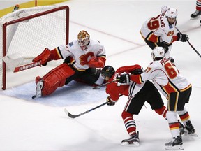 Chicago Blackhawks' Richard Panik's shot on goal goes wide of the skate of Calgary Flames goalie Brian Elliott and the goal, as Michael Frolik (67) checks Panik from behind during the third period of an NHL hockey game Monday, Oct. 24, 2016, in Chicago.