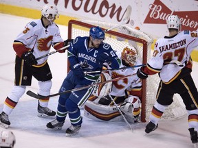 Calgary Flames centre Sam Bennett (93) and Calgary Flames defenceman Dougie Hamilton (27) keep Vancouver Canucks centre Henrik Sedin (33) from getting a shot on net during second period NHL action, in Vancouver on Saturday, Oct. 15, 2016.