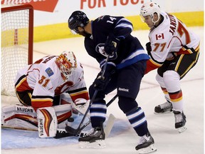 Calgary Flames' goaltender Chad Johnson (31) stops Winnipeg Jets' Anthony Peluso (14) with Flames' Mark Jankowski (77) in front of the net during first period pre-season NHL hockey in Winnipeg, Tuesday, September 27, 2016.