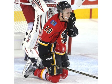 MatthewTkachuk of the Calgary Flames holds his face after getting cross checked in front of Carolina Hurricanes netminder Eddie Lack in the first period at the Saddledome Thursday night October 19, 2016.