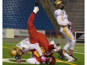 Eric Plett of the Manitoba Bisons and Austen Hartley of the Dinos take a tumble at McMahon Stadium in Calgary, Alta., on Friday, Oct. 14, 2016.