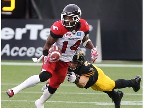 Calgary Stampeders running back Roy Finch (14) gaining yards while defending by Hamilton Tiger-Cats defensive back Mike Daly (35) during the first-half of CFL football action in Hamilton, Ont., on Saturday, October 1, 2016.