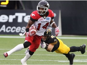 Calgary Stampeders running back Roy Finch (14) gaining yards while defending by Hamilton Tiger-Cats defensive back Mike Daly (35) during the first-half of CFL football action in Hamilton, Ont., on Saturday, October 1, 2016.