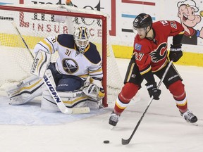 Calgary Flames Dougie Hamilton passes the puck past Buffalo Sabres goalie Chad Johnson to Calgary Flames Markus Granlund for the assist of the second goal against the Buffalo Sabres at the Saddledome in Calgary, on December 10, 2015.