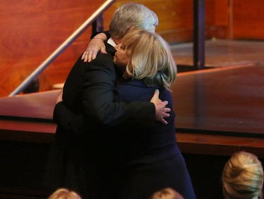 Former prime minister Stephen Harper hugs Karen Prentice during the state memorial for her husband, former premier Jim Prentice.