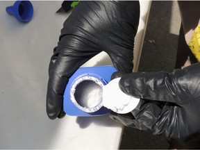 In this June 27, 2016 photo provided by the Royal Canadian Mounted Police, a member of the RCMP in Vancouver opens a printer ink bottle containing the opioid carfentanil imported from China.